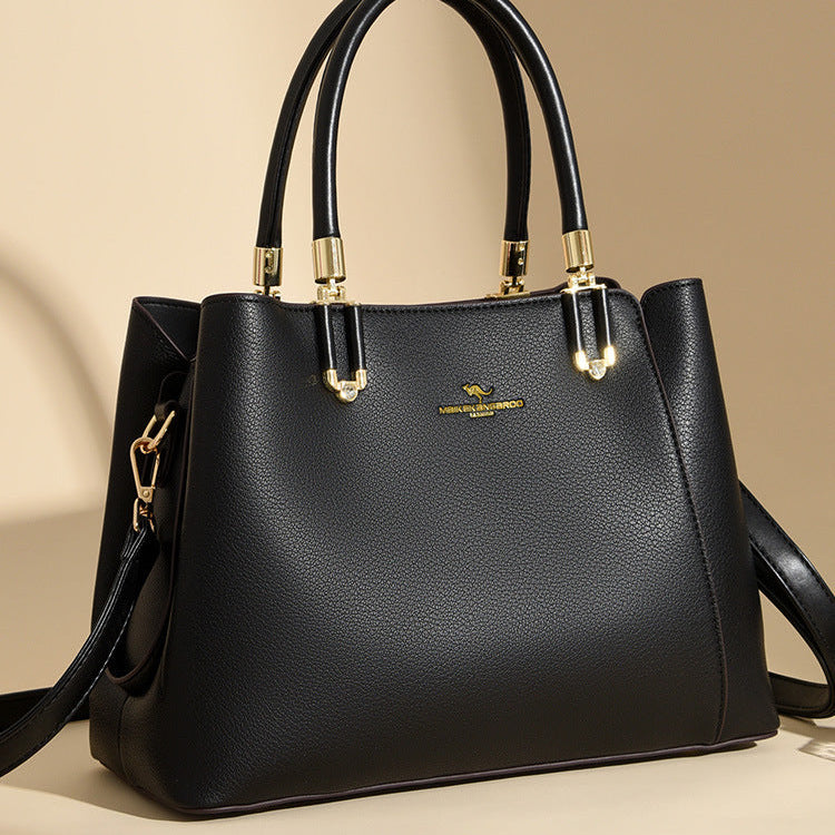 Black handbag with gold accents on a beige background
