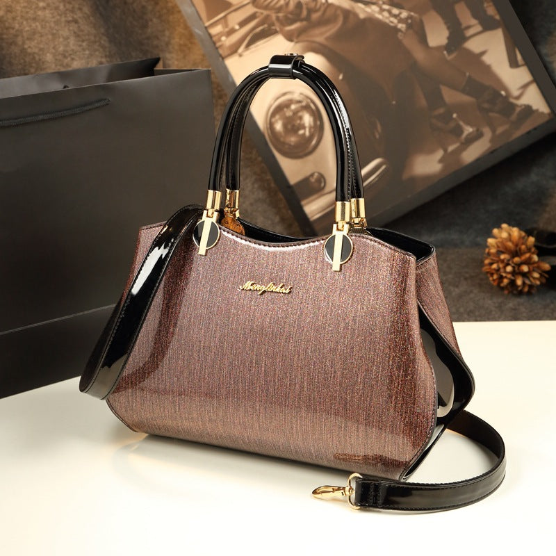 Brown handbag with gold accents on a white surface, with a blurred background